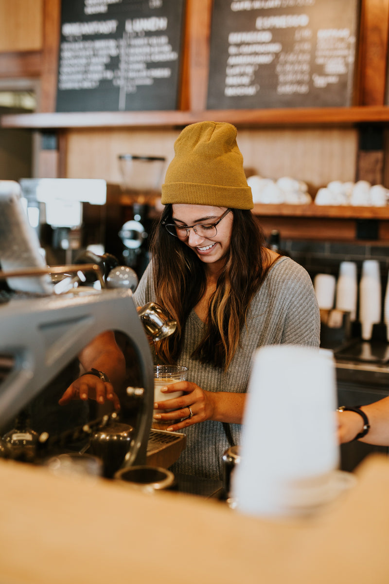 Barista préparant un café derrière le comptoir d’un café engagé dans une démarche de restauration responsable.