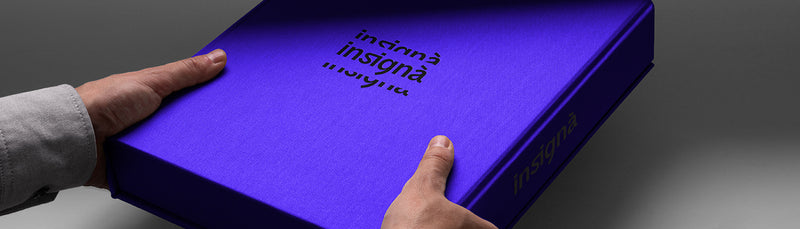 Boîte de packaging violette Insignà tenue à deux mains, logo gravé sur le couvercle.