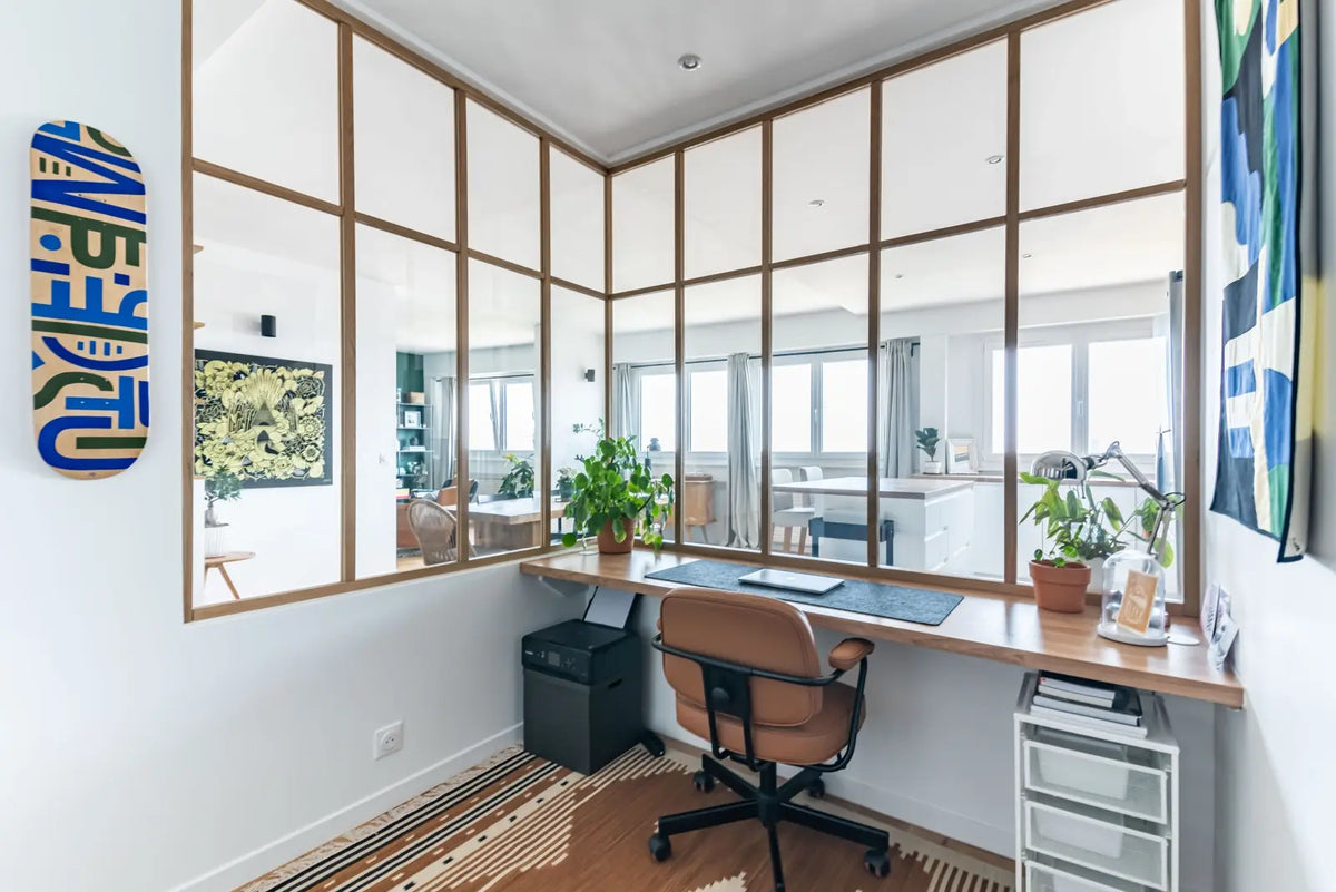 Espace de travail lumineux et design dans un studio de création graphique, avec bureau minimaliste et verrière intérieure contemporaine.