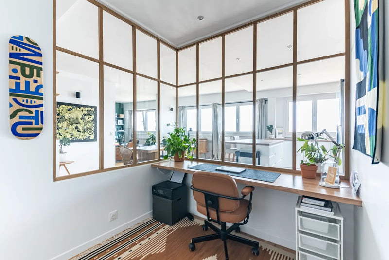 Espace de travail lumineux et design dans un studio de création graphique, avec bureau minimaliste et verrière intérieure contemporaine.