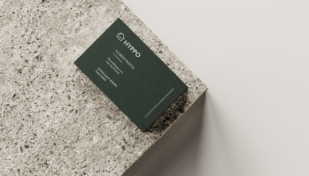 Carte de visite Hyppo posée sur une surface en pierre illustrant l’identité visuelle d’une entreprise de financement immobilier.