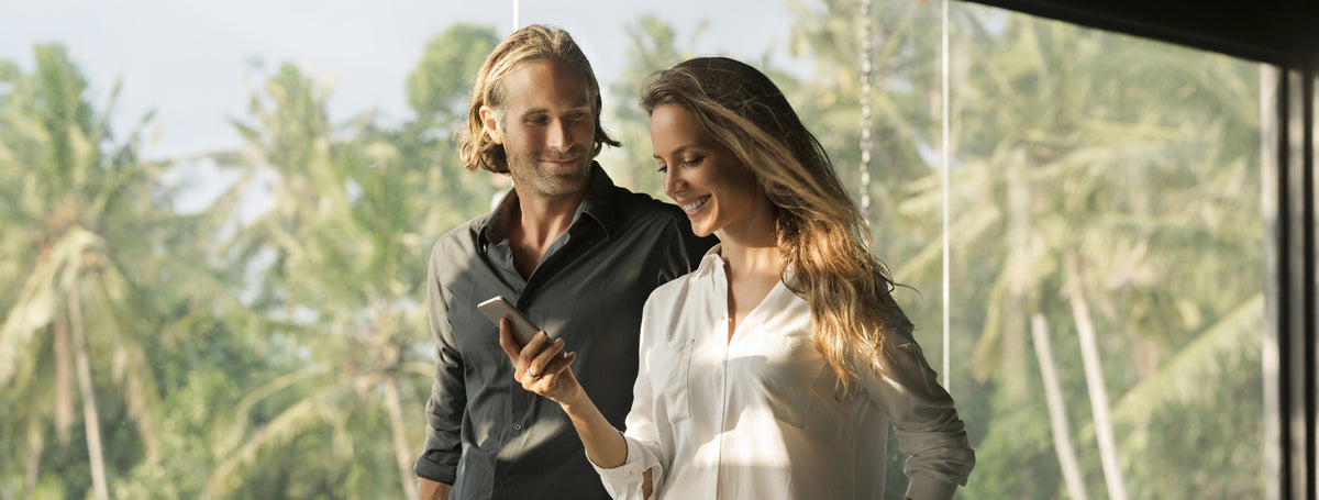 Couple regardant un smartphone et discutant d’un projet immobilier ou de financement de leur logement.