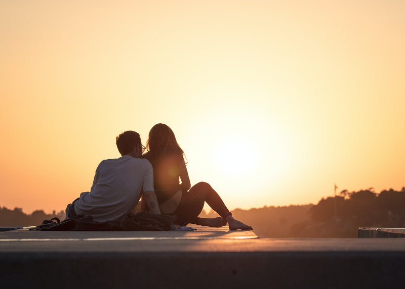 Couple assis face au coucher de soleil illustrant une ambiance lifestyle pour une campagne de marque.