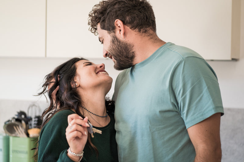 Jeune couple souriant célébrant l’achat de leur maison avec les clés en main dans leur nouveau logement.