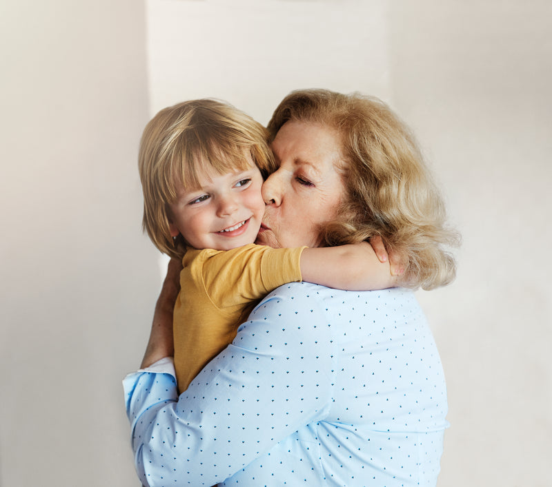 Grand-mère embrassant son petit-fils dans un moment tendre, évoquant la famille et la transmission patrimoniale.
