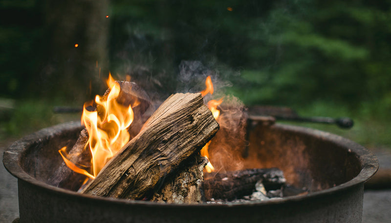 Feu de camp en pleine nature, symbole d’aventure et de moments partagés en colonie de vacances pour enfants avec Hakuna, club dédié aux jeunes explorateurs.