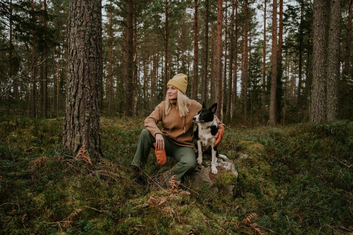 Femme avec son chien en forêt, illustrant un mode de vie naturel et le bien-être animal soutenu par une alimentation durable comme Kookapi.