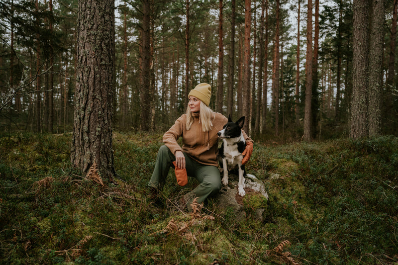 Femme avec son chien en forêt, illustrant un mode de vie naturel et le bien-être animal soutenu par une alimentation durable comme Kookapi.