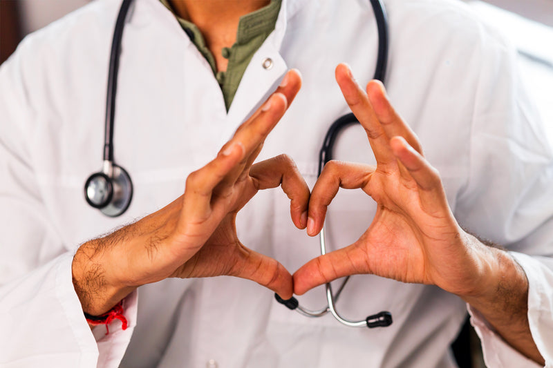 Professionnel de santé avec stéthoscope formant un cœur avec ses mains pour symboliser le soin et la santé.