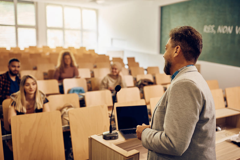 Professeur donnant un cours en amphithéâtre devant des étudiants dans une université ou école de commerce.