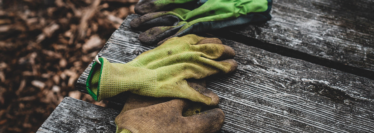 Gants de jardinier posés sur une table en bois, symbolisant le travail manuel et l’entretien des espaces verts par un paysagiste.