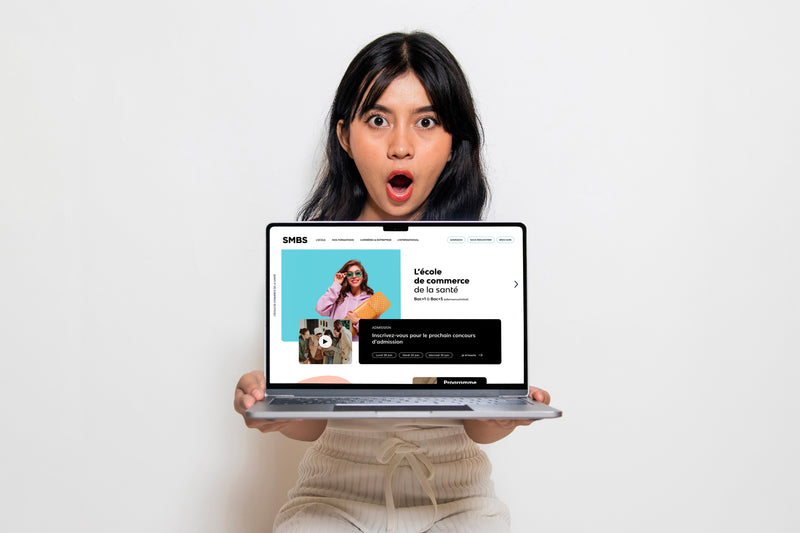 Étudiante présentant le site web de l’école de commerce de la santé SMBS affiché sur un ordinateur portable.