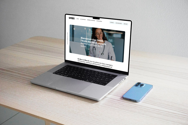 Ordinateur portable affichant le site web d’une école de management de la santé sur un bureau minimaliste.