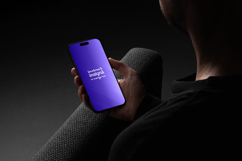 Écran de smartphone affichant le logo Insignà en dégradé bleu-violet, tenu dans l'obscurité.