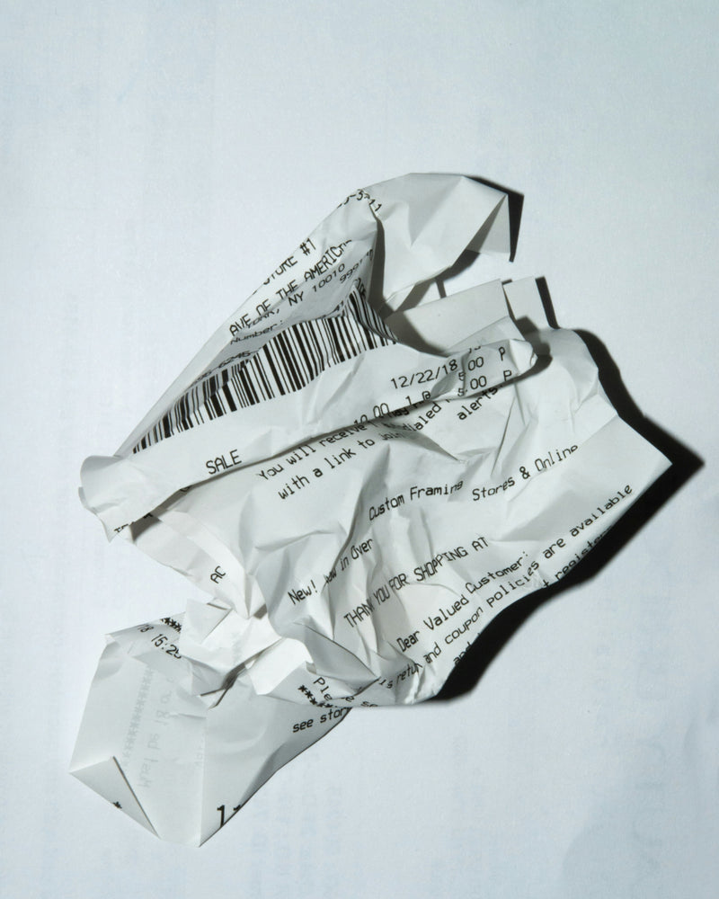 Ticket de caisse froissé en gros plan, avec code-barres et texte imprimé visibles sur fond blanc.