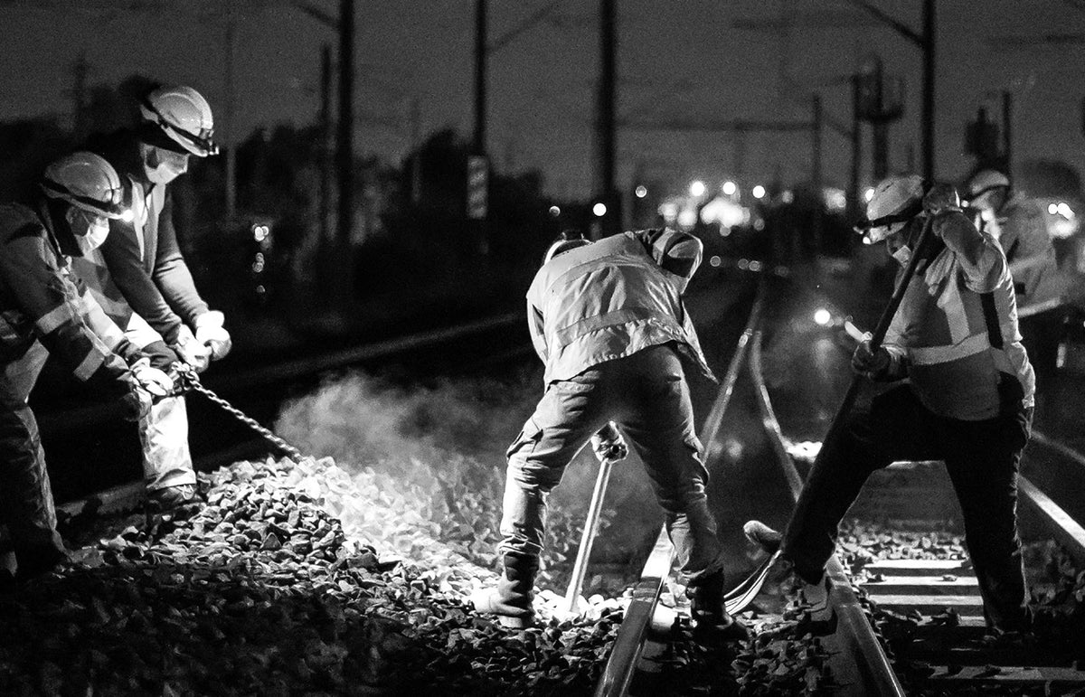 Techniciens travaillant de nuit sur une voie ferrée pour la maintenance et la modernisation du réseau ferroviaire.