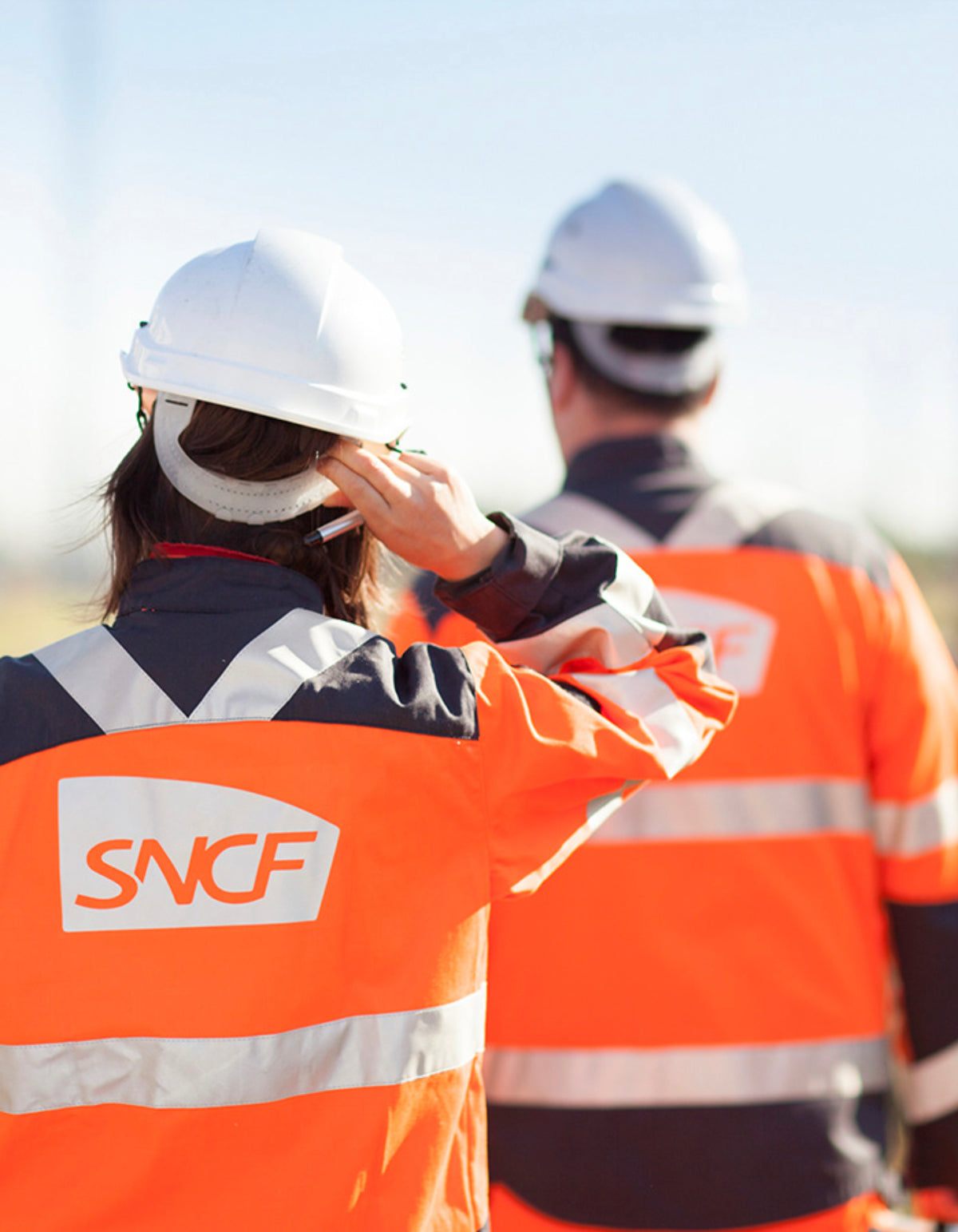 Techniciens SNCF en gilet haute visibilité et casque de sécurité intervenant sur un chantier du réseau ferroviaire.