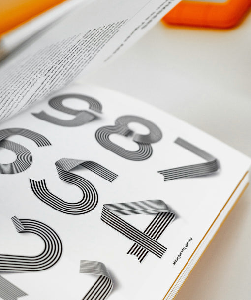 Double page de livre présentant une typographie graphique contemporaine avec lettres stylisées, dans un projet de design éditorial.