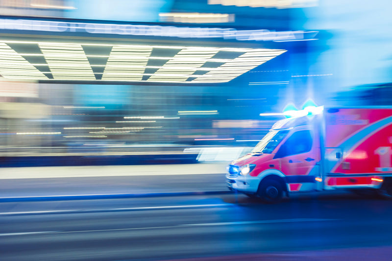 Ambulance en intervention de nuit, gyrophares allumés, en filé de mouvement.